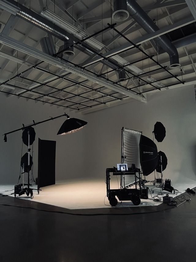 A large film studio with overhead lighting rigs, softboxes and a camera on a dolly
