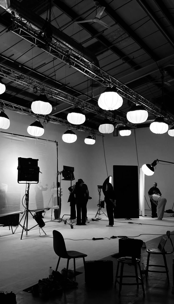Black-and-white view of a film crew working under round studio lights