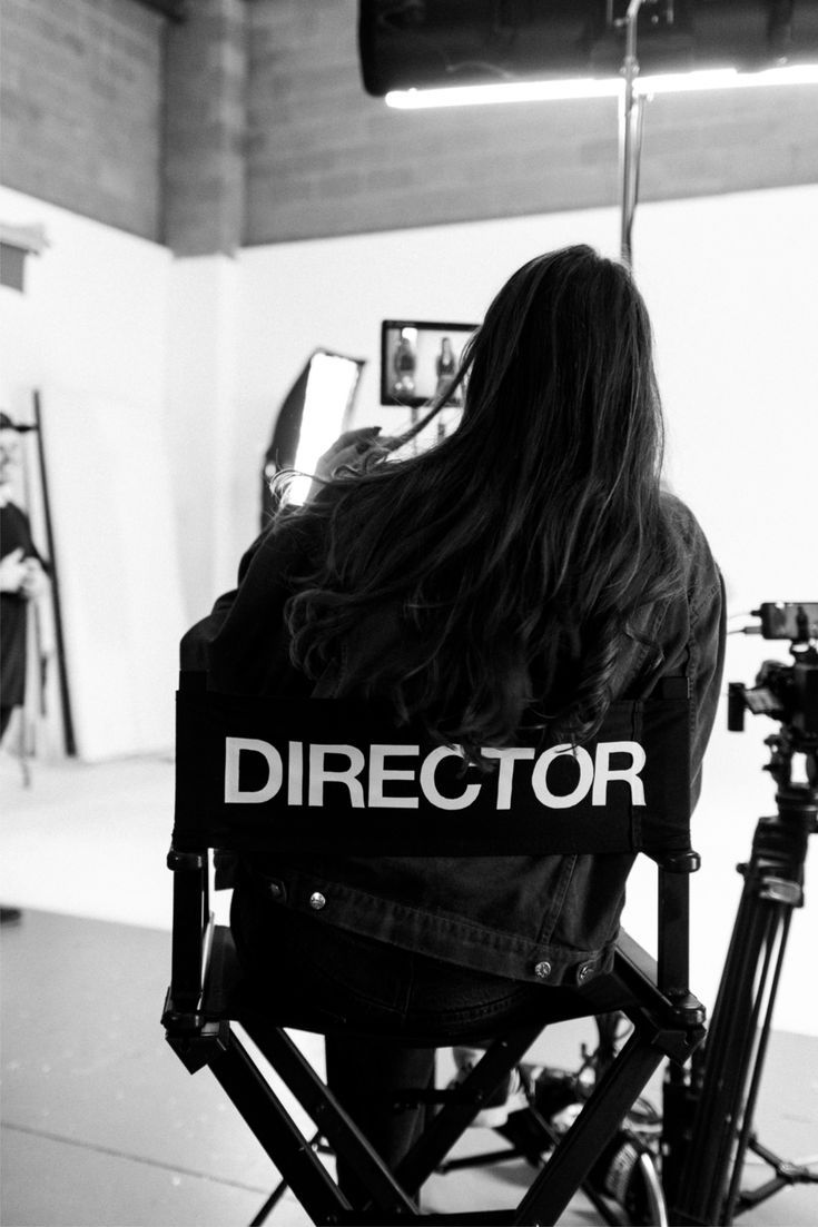 A director seen from behind, seated on a bright film studio set