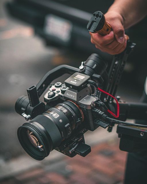 A camera operator holding a cinema camera on a gimbal rig.