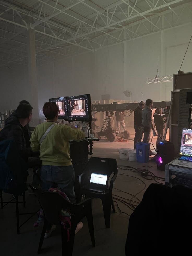 A film crew gathered around monitors on a large studio floor.